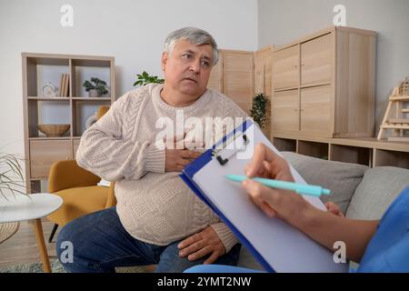 Medico in visita a un anziano dopo un attacco di cuore Foto Stock