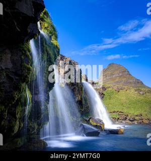 Cascata Kirkjufellsfoss. Mountain Kirkjufell sullo sfondo. Grundarfjörður, Islanda. Foto Stock