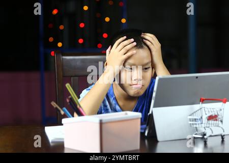 Un ragazzo mostra frustrazione mentre studia a casa, sentendosi sopraffatto dal suo tablet. La scena cattura le sfide dell'apprendimento in un'ag digitale Foto Stock