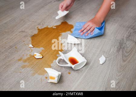Una tazza di caffè rotta è caduta sul laminato e il caffè è versato sul pavimento. Foto Stock