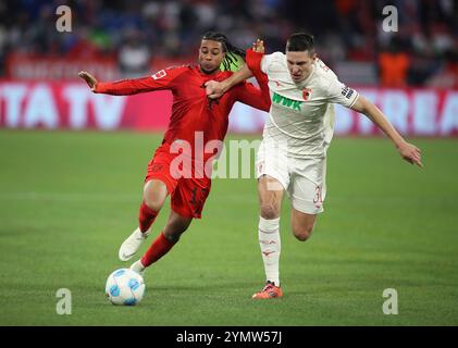 München, Deutschland, 22. Novembre 2024: Fussball, Herren, Bundesliga, Saison 2024/2025, FC Bayern München - FC Augsburg, Allianz Arena Michael Olise (FC Bayern München) (li.) mit Keven Schlotterbeck (FC Augsburg) (re.) im Zweikampf um den Ball DFB, le normative DFL vietano qualsiasi uso di fotografie come sequenze di immagini e/o quasi-video Foto Stock