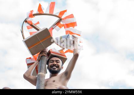 uomo sorridente che si avvicina alla casella premio in una arrampicata con betel nut Foto Stock