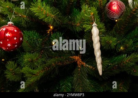 Un albero di Natale con un ornamento bianco appeso ad esso. L'albero è decorato con ornamenti rossi e bianchi Foto Stock