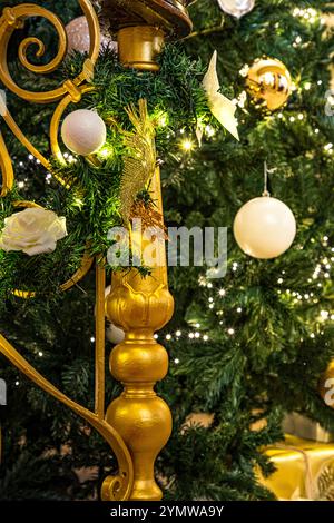 Immagine natalizia del palo in oro newel e banister di una scala con ghirlande di decorazioni verdi, dorate e crema e luci scintillanti Foto Stock