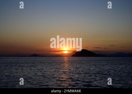 Tramonto dietro un'isola nel Parco Nazionale di Komodo, Indonesia Foto Stock