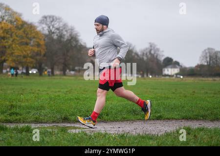 Londra, Regno Unito. 23 novembre 2024 Un jogger che corre a Wimbledon Common, a sud-ovest di Londra in condizioni di pioggia e vento mentre Storm Bert colpisce il Regno Unito. L'ufficio MET ha attivato avvisi meteo per vento, pioggia e neve in tutto il Regno Unito con 16 avvisi di inondazione e raffiche di vento fino a 70 km/h di credito . Amer Ghazzal/Alamy Live News Foto Stock