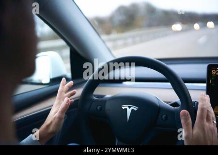 Baviera, Germania - 22 novembre 2024: Immagine simbolica per la guida autonoma con una Tesla. Il conducente di un'auto elettrica Tesla tiene le mani lontane dal volante durante la guida autonoma *** Symbolbild für autonomo Fahren mit einem Tesla. Der Fahrer eines Tesla Elektroautos hält Seine Hände weg vom Lenkrad, während das Fahrzeug selbstständig fährt Foto Stock