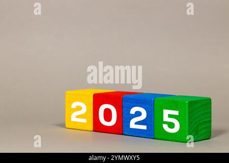 Dal 2024 al 2025, numeri bianchi su blocchi dai colori vivaci, buon Natale e felice anno nuovo, sfondo grigio Foto Stock