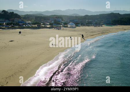 Contea di Yangyang, Corea del Sud - 3 novembre 2024: Lo scintillante litorale di Namae Beach riflette la luce del sole mentre le dolci onde si infrangono sulla sabbia, con l'ingegno Foto Stock