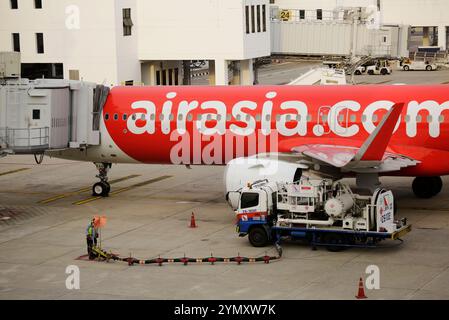 Bangkok, Thailandia - 29 giugno 2023: Un aereo della compagnia aerea low cost AirAsia è parcheggiato al cancello prima della partenza all'aeroporto Don Mueang. Foto Stock