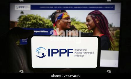 Stoccarda, Germania, 07-15-2024: Persona che tiene un cellulare con il logo della Federazione internazionale dei genitori pianificati (IPPF) davanti alla pagina web. Concentrati su Foto Stock