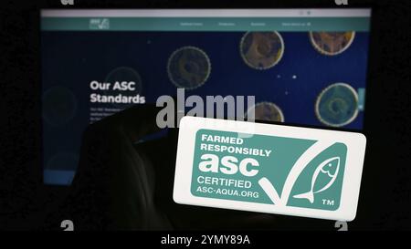 Stoccarda, Germania, 07-01-2024: Persona che detiene un telefono cellulare con il logo dell'organizzazione Aquacoltura Stewardship Council (ASC) di fronte alla pagina web. Focu Foto Stock