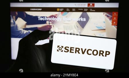 Stoccarda, Germania, 02-24-2024: Persona che tiene un telefono cellulare con il logo della società australiana di soluzioni per lo spazio di lavoro Servcorp Limited davanti alla pagina web. Foto Stock