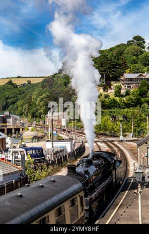 Treno a vapore d'epoca con fumo che arriva alla stazione di Dartmouth in una giornata di sole con vedute panoramiche Foto Stock