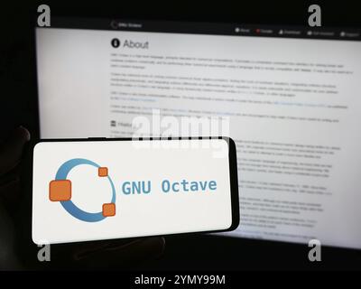 Stoccarda, Germania, 03-13-2024: Persona con smartphone con logo del linguaggio di programmazione scientifica GNU Octave davanti al sito web. Concentrati sul telefono Foto Stock