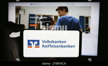 Stoccarda, Germania, 07-15-2024: Persona che detiene un cellulare con il logo della rete bancaria tedesca Volksbanken Raiffeisenbanken davanti alla pagina web aziendale Foto Stock
