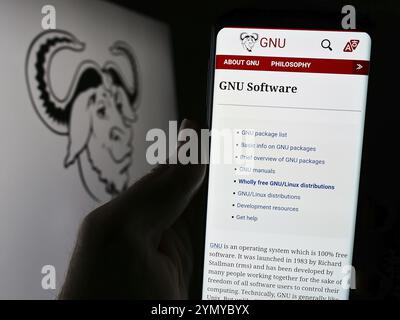 Stoccarda, Germania, 04-05-2024: Persona che tiene il cellulare con pagina web del progetto di collaborazione software GNU Project davanti al logo. Concentrati sul centro Foto Stock