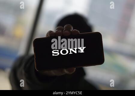 SONY è una società giapponese. SONY è un'azienda produttrice di console di videogiochi e di videogiochi. Smartphone con logo SONY sullo schermo circondato da gamepad. Foto Stock