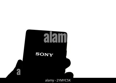SONY è una società giapponese. SONY è un'azienda produttrice di console di videogiochi e di videogiochi. Smartphone con logo SONY sullo schermo circondato da gamepad. Foto Stock