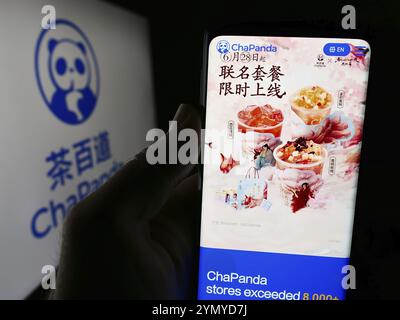 Stoccarda, Germania, 07-11-2024: Persona che tiene il cellulare con pagina web di Chengdu Chabaidao Catering Management Co. Ltd. (ChaPanda) con logo. Concentrati su Foto Stock