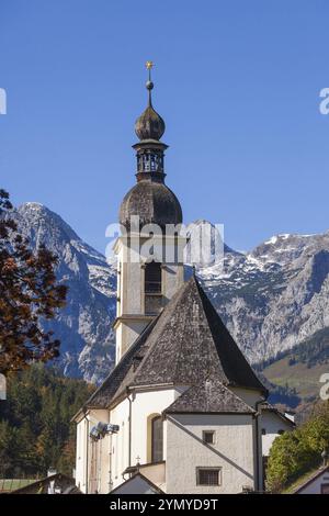 Chiesa parrocchiale di San Sebastiano in autunno con il fiume Ramsauer Ache, dietro le montagne di Reiteralpe, Ramsau, Berchtesgaden, Berchtesgadener Land Foto Stock