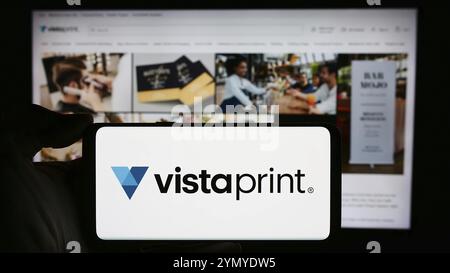 Stoccarda, Germania, 04-12-2024: Persona che detiene un cellulare con il logo della società di personalizzazione di massa Vistaprint (Vista) di fronte alla pagina web aziendale. Focu Foto Stock