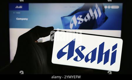 Stoccarda, Germania, 03-18-2024: Persona che detiene un telefono cellulare con il logo della società giapponese di birra Asahi Group Holdings Ltd. Di fronte a Busness Web pa Foto Stock