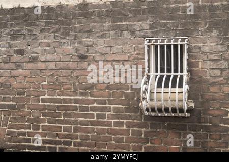 Piccola finestra sbarrata su un muro di mattoni Foto Stock