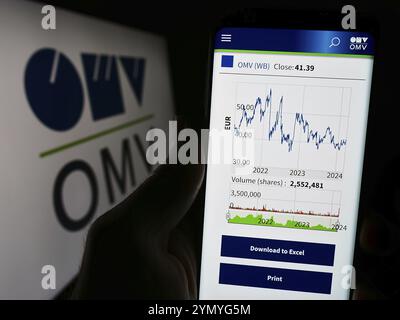 Stoccarda, Germania, 03-16-2024: Persona che detiene il cellulare con pagina web della società austriaca di petrolio e gas OMV Aktiengesellschaft davanti al logo. Messa a fuoco o Foto Stock