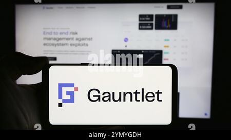 Stoccarda, Germania, 03-28-2024: Persona che tiene il cellulare con il logo della società statunitense di soluzioni Defi Gauntlet Networks Inc. Di fronte alla pagina web aziendale. F Foto Stock