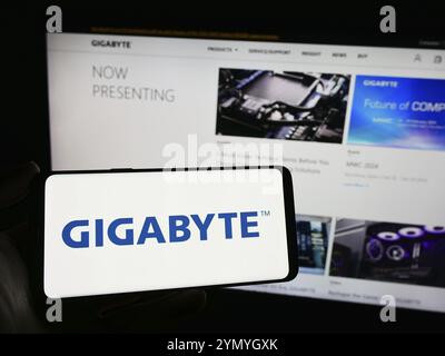 Stoccarda, Germania, 02-24-2024: Persona che detiene un telefono cellulare con il logo della società taiwanese di hardware per computer Gigabyte Technology davanti alla pagina web. Foto Stock