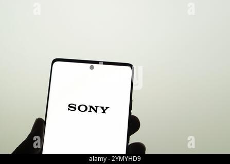 SONY è una società giapponese. SONY è un'azienda produttrice di console di videogiochi e di videogiochi. Smartphone con logo SONY sullo schermo circondato da gamepad. Foto Stock