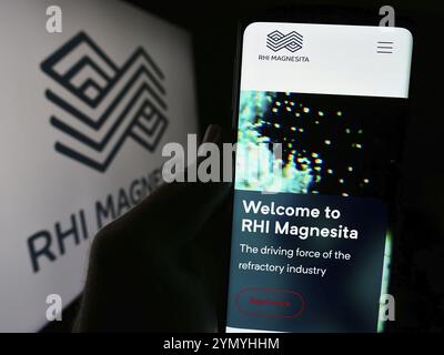 Stoccarda, Germania, 04-07-2024: Persona che detiene il cellulare con pagina web della società di prodotti refrattari RHI Magnesita N.V. davanti al logo. Concentratevi sul cen Foto Stock