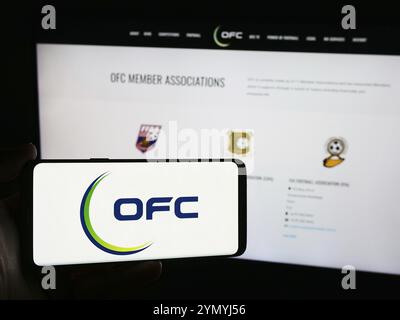 Stoccarda, Germania, 06-25-2024: Persona che detiene un telefono cellulare con il logo dell'associazione Oceania Football Confederation (OFC) davanti alla pagina web. Concentrati Foto Stock