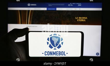 Stoccarda, Germania, 06-25-2024: Persona che tiene il cellulare con il logo della Confederacion Sudamericana de Futbol (CONMEBOL) davanti alla pagina web. Attenzione al ph Foto Stock