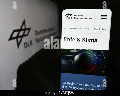 Stoccarda, Germania, 06-26-2024: Persona che tiene un cellulare con pagina web di Deutsches Zentrum fuer Luft- und Raumfahrt e.V. (DLR) davanti al logo. Concentrati Foto Stock