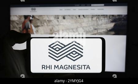 Stoccarda, Germania, 04-07-2024: Persona che detiene un cellulare con il logo della società di prodotti refrattari RHI Magnesita NV di fronte alla pagina web aziendale. Concentrati Foto Stock