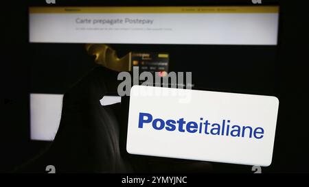 Stoccarda, Germania, 06-01-2024: Persona che detiene il cellulare con il logo della società italiana di servizi postali Poste italiane Spa davanti alla pagina web aziendale. Foto Stock