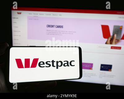 Stoccarda, Germania, 03-16-2024: Persona che detiene un telefono cellulare con il logo della società finanziaria australiana Westpac Banking Corporation davanti alla pagina web Foto Stock