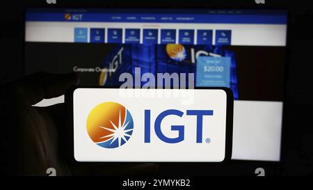 Stoccarda, Germania, 07-06-2024: Persona che detiene un cellulare con il logo della società International Game Technology plc (IGT) di fronte alla pagina web aziendale. Fil Foto Stock