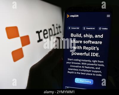 Stoccarda, Germania, 03-12-2024: Persona che possiede uno smartphone con pagina web della società statunitense di piattaforme di sviluppo software Replit Inc. Davanti al logo. Concentrati Foto Stock