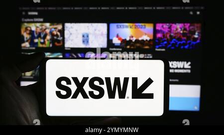 Stoccarda, Germania, 03-14-2024: Persona che tiene un cellulare con il logo del film annuale e dell'evento mediatico South by Southwest (SXSW) davanti alla pagina web. Concentrati Foto Stock