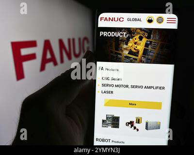 Stoccarda, Germania, 07-25-2024: Persona che detiene il cellulare con pagina web della società giapponese di robotica FANUC Corporation davanti al logo. Concentrati sul centro Foto Stock