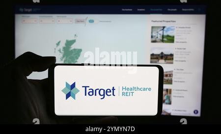 Stoccarda, Germania, 05-29-2024: Persona che detiene lo smartphone con il logo della società immobiliare britannica Target Healthcare REIT davanti al sito web. Concentrati su p Foto Stock