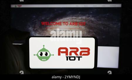 Stoccarda, Germania, 05-03-2024: Persona che detiene un cellulare con il logo della società Internet of Things ARB IOT Group Limited di fronte alla pagina web aziendale. F Foto Stock