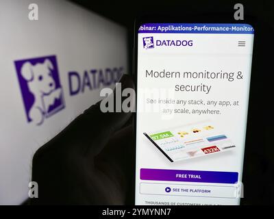 Stoccarda, Germania, 07-25-2024: Persona che detiene il cellulare con pagina web della società statunitense di servizi di osservazione Datadog Inc. Davanti al logo. Concentrati sul cent Foto Stock
