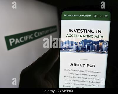 Stoccarda, Germania, 03-07-2024: Persona che detiene il cellulare con pagina web della società di investimento Pacific Century Group (PCG) davanti al logo. Concentratevi sul cen Foto Stock