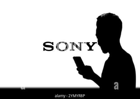 SONY è una società giapponese. SONY è un'azienda produttrice di console di videogiochi e di videogiochi. Smartphone con logo SONY sullo schermo circondato da gamepad. Foto Stock