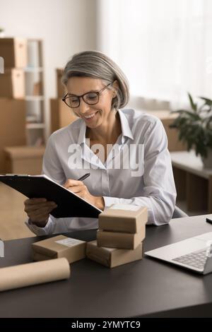 Allegro proprietario di un negozio Internet dai capelli grigi che tiene i registri Foto Stock