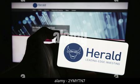 Stoccarda, Germania, 03-19-2024: Persona che detiene un telefono cellulare con il logo della società britannica Herald Investment Trust plc di fronte alla pagina web aziendale. Fil Foto Stock